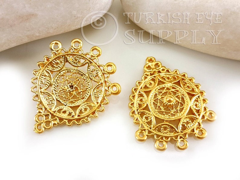 May include: Two gold filigree metal charms with a circular design and multiple loops. The charms are in the shape of a diamond.