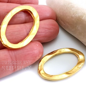 May include: Two gold-toned oval-shaped metal rings with a hammered texture. The rings are approximately 2 inches in diameter.