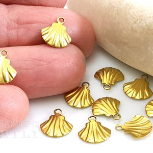 May include: Ten gold-coloured metal seashell charms with a loop at the top for attaching to jewellery or other crafts. The charms are approximately 2.5 cm in size and have a detailed, textured design.
