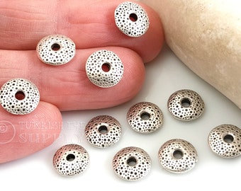 May include: Silver metal beads with a textured surface and a hole in the center. The beads are round and have a diameter of approximately 1 inch.