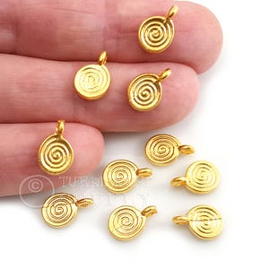 May include: A collection of small, gold-colored spiral charms. Each charm has a loop at the top for attaching to jewelry. The charms are oval-shaped with a raised spiral design in the center. These charms are ideal for DIY jewelry making.