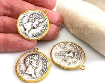 May include: Three silver Roman coin charms with gold-colored rims. Each charm has a different design, including a profile of a man and a standing figure. The charms have jump rings for attaching to jewelry.