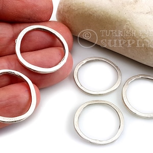 May include: Four silver jump rings, each with a slightly irregular, hammered finish. The rings are approximately 2.5 cm in diameter.