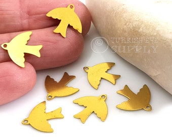 May include: Six gold-colored metal bird charms with a loop for hanging. The charms are in the shape of a stylized bird with wings spread.