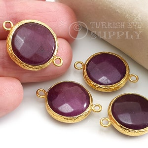 May include: Four gold-toned pendant charms with a round, purple gemstone cabochon in the centre. Each charm has two gold loops for attaching to a necklace or bracelet.