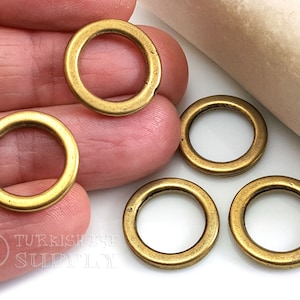 May include: Four gold-colored metal jump rings. The rings are about 1 inch in diameter and have a smooth, polished finish.