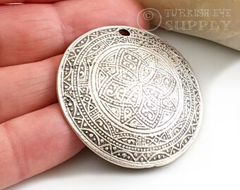 May include: Silver pendant with an intricate geometric design. The pendant is round and has a hole at the top for hanging.