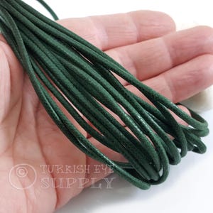 May include: Dark green waxed cord, tightly bundled, held in a hand. The cord appears smooth and flexible, suitable for jewelry making or crafts. The image includes the text "TURKISH EYE SUPPLY".