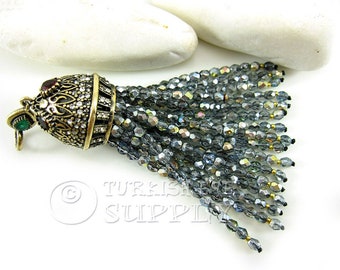 May include: A silver and gold tassel pendant with a detailed ornate top and a long fringe of faceted glass beads.