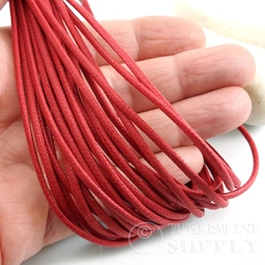 May include: Close-up of a bundle of red waxed cotton cord. The cords are tightly woven and appear to be approximately 1mm in diameter. The cords are a vibrant, solid red color and are suitable for jewelry making or crafting.