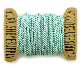 May include: A spool of mint green braided cord with the text "TURKISH EYES SUPPLY" printed on the ends.