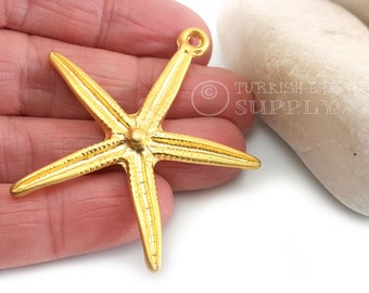 May include: Gold-tone metal starfish charm with a textured surface and a loop at the top for hanging. The charm is approximately 5 cm in length.