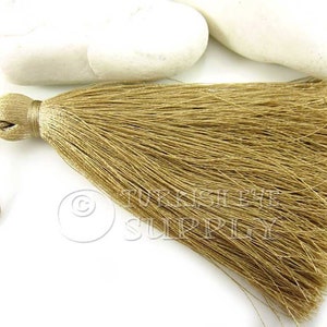 May include: A beige silk tassel with a long, flowing fringe. The tassel is attached to a thin cord.
