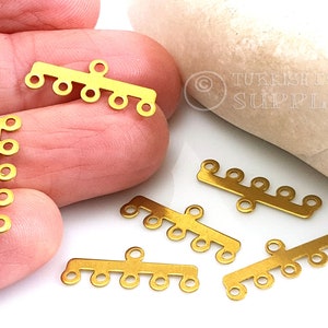 May include: Five gold metal connector pieces with multiple loops. Each piece has a straight bar with five loops on one side and two loops on the other side.