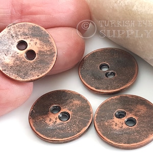 May include: Four copper-colored buttons with two holes each. The buttons have a distressed, aged look.