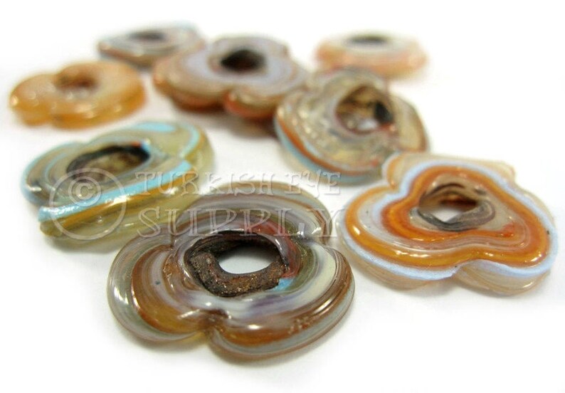 May include: Assortment of colorful glass flower-shaped beads with a hole in the center. The beads have a layered, swirled pattern in shades of brown, blue, and white.
