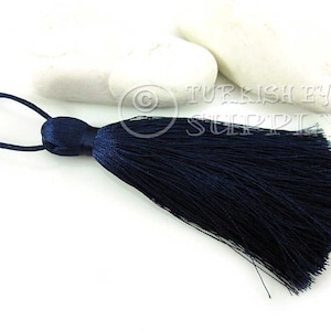 May include: A dark blue tassel with a loop at the top. The tassel is made of soft, silky threads and is approximately 2 inches long.
