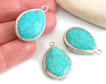 Op de afbeelding: Drie turquoise traanvormige hangers met zilverkleurige metalen instellingen. Elke hanger heeft een lus om aan een ketting of koord te bevestigen.