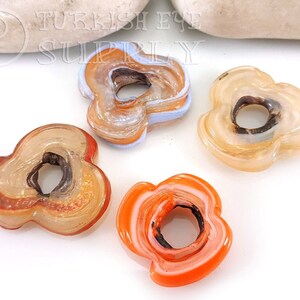 May include: Four agate flower-shaped beads with a hole in the center. The beads are in shades of orange, brown, and white.