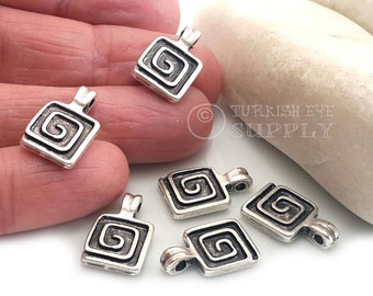 Puede incluir: Cinco colgantes de metal plateados con forma cuadrada y un diseño en espiral. Los colgantes tienen un bucle en la parte superior para sujetarlos a una cadena o cordón.