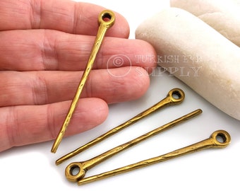 May include: Four gold-colored metal decorative pieces with a hammered texture. Each piece has a small loop at one end and a pointed end. The pieces are approximately 2 inches long.