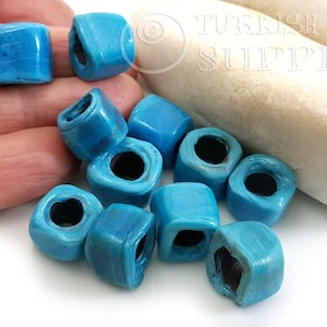 Peut inclure: Dix perles carr&eacute;es de couleur bleu turquoise avec un trou au centre. Les perles sont en c&eacute;ramique et ont une surface l&eacute;g&egrave;rement textur&eacute;e.