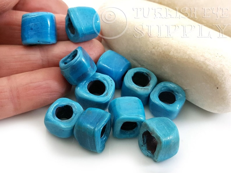 Peut inclure: Dix perles carr&eacute;es de couleur bleu turquoise avec un trou au centre. Les perles sont en c&eacute;ramique et ont une surface l&eacute;g&egrave;rement textur&eacute;e.