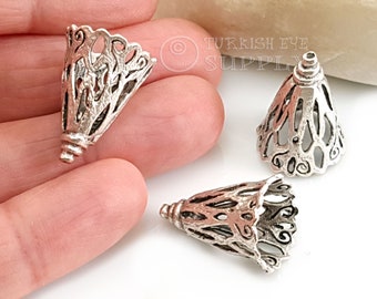 Op de afbeelding: Drie zilveren metalen kegelvormige kralencaps met een ingewikkeld, opengewerkt ontwerp. De caps zijn ongeveer 2,5 cm hoog.