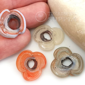 May include: Four agate flower beads with a hole in the center. The beads are in shades of white, orange, and gray.