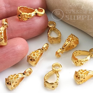 Puede incluir: Nueve baúles de colgante de metal dorado con diseños intrincados. Los baúles son de diferentes formas y tamaños, pero todos tienen un estilo adornado similar.