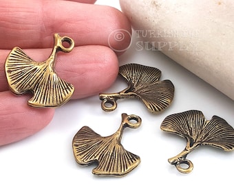 May include: Four gold-toned metal ginkgo leaf charms with a loop for attaching to jewelry or other crafts.  The leaves have a detailed, textured design.