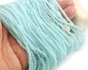 May include: Strands of light blue faceted beads. The beads are small and uniform in size, creating a delicate and shimmering effect. The beads are held together, suggesting they are ready for jewelry making or crafting projects.