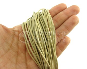 May include: A close-up of a hand holding a bundle of light beige leather cord. The cord is approximately 1/8 inch thick and is ideal for jewelry making, leather crafting, and other DIY projects.