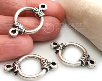 May include: Three silver-toned metal clasps with ornate designs. Each clasp has a circular ring and two decorative ends.