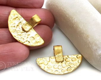 May include: Two gold-toned metal pendants shaped like half-circles, featuring a textured surface. The pendants have a loop at the top for attaching to a chain.