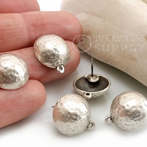 May include: Four silver-toned metal earring components with a hammered texture. Each component has a loop on the top and a post on the bottom. The components are arranged on a white surface.