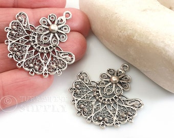May include: Two silver filigree metal charms in the shape of a fan with a flower at the top. The charms have a delicate, intricate design and are perfect for jewelry making.