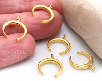 May include: Five gold crescent moon charms with a loop for attaching to jewelry. The charms are about 1 inch in diameter.