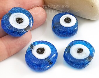 May include: Four blue glass evil eye beads with white and black centers. The beads are approximately 1 inch in diameter.
