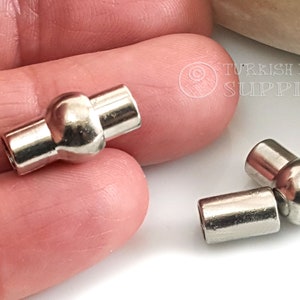 May include: Two silver metal magnetic clasps for jewelry making. Each clasp has a round ball in the center and two cylindrical ends.