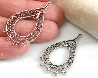 May include: Two silver-toned, teardrop-shaped jewelry components. Each component features an openwork design with swirling patterns and small loops for attaching additional elements. The components are displayed against a neutral background.