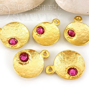 Puede incluir: Cinco abalorios de metal dorado con forma redonda y un strass rosa en el centro. Cada abalorio tiene un bucle en la parte superior para sujetarlo a un collar o pulsera.