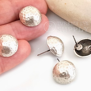 May include: Four silver hammered metal earring studs. The studs are round and have a textured surface. The earring posts are visible.