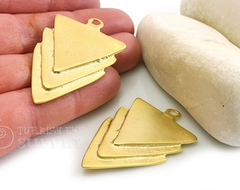 Può includere: Due ciondoli pendenti a forma di triangolo in metallo dorato con un design a strati. I ciondoli hanno una superficie testurizzata e un anello nella parte superiore per attaccarli ai gioielli.