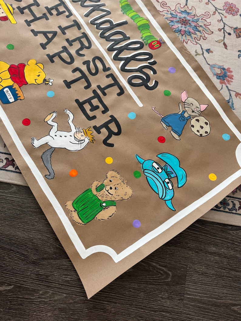 May include: Brown paper banner with the text "Madale's FIRST Easter" in black script. The banner features cartoon illustrations of Winnie the Pooh, a caterpillar, a mouse, and other characters. Colorful polka dots are scattered around the illustrations.