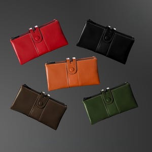 May include: Five leather wallets in red, black, brown, orange, and green. Each wallet has a rectangular shape with a zipper closure and a snap button flap. The wallets are displayed against a gray background.