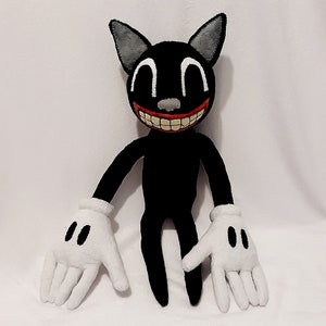 May include: A black cartoon cat plush toy with a wide, toothy grin. The cat has large white eyes and white gloves. The plush toy is sitting on a white surface.
