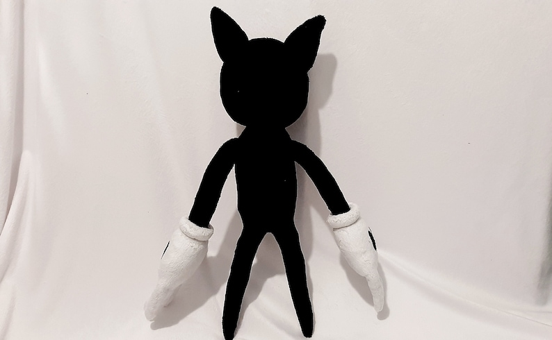 May include: A black plush toy with white gloves. The toy has a cartoon-like appearance with large ears and a slender body.