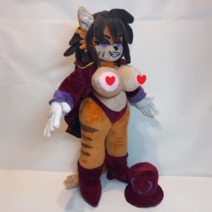 May include: A plush toy with a tiger-like pattern, wearing a purple and burgundy outfit with a large hat. The toy has a long, dark mane and a mischievous expression.