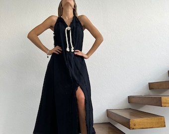 Può includere: Un abito midi nero senza maniche con scollo all'americana e chiusura con coulisse in corda bianca. Il capo presenta bordi sfrangiati lungo lo scollo e la cucitura verticale anteriore, che include un alto spacco che parte dall'orlo inferiore.